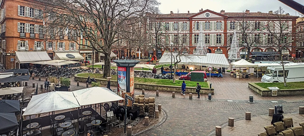 La place Saint-Georges avec ses façades et des étals de marché.